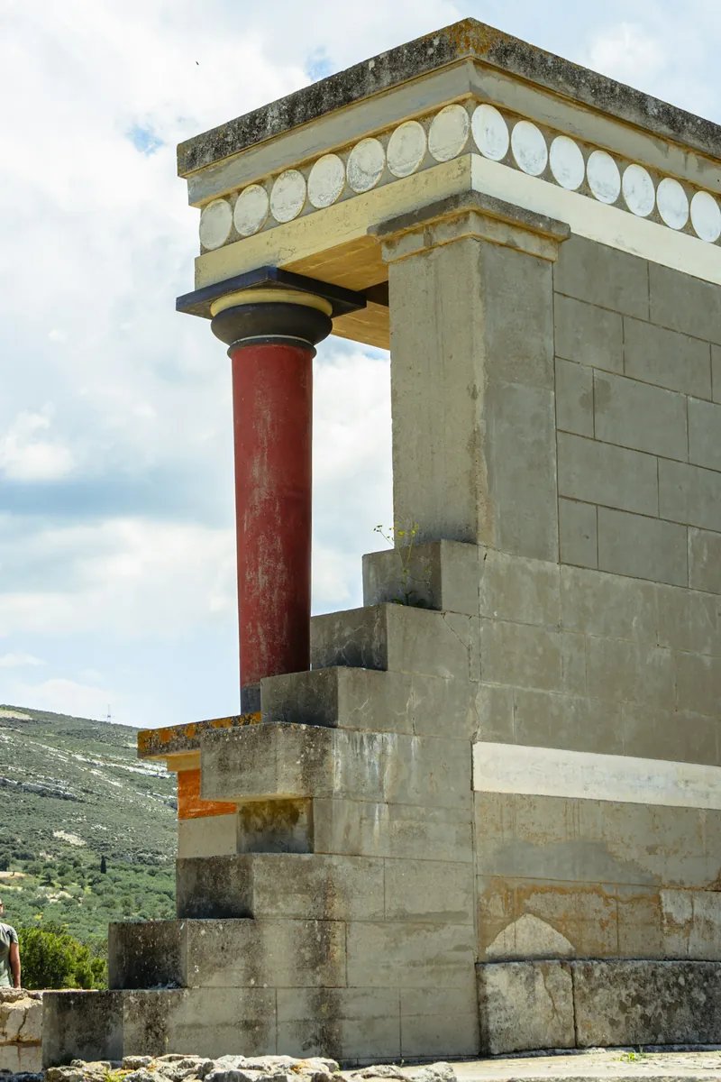 Die restaurierten roten Säulen und der Nordeingang des Palastes von Knossos auf Kreta, mit dem Fresko des angreifenden Stiers über der Säulenhalle.